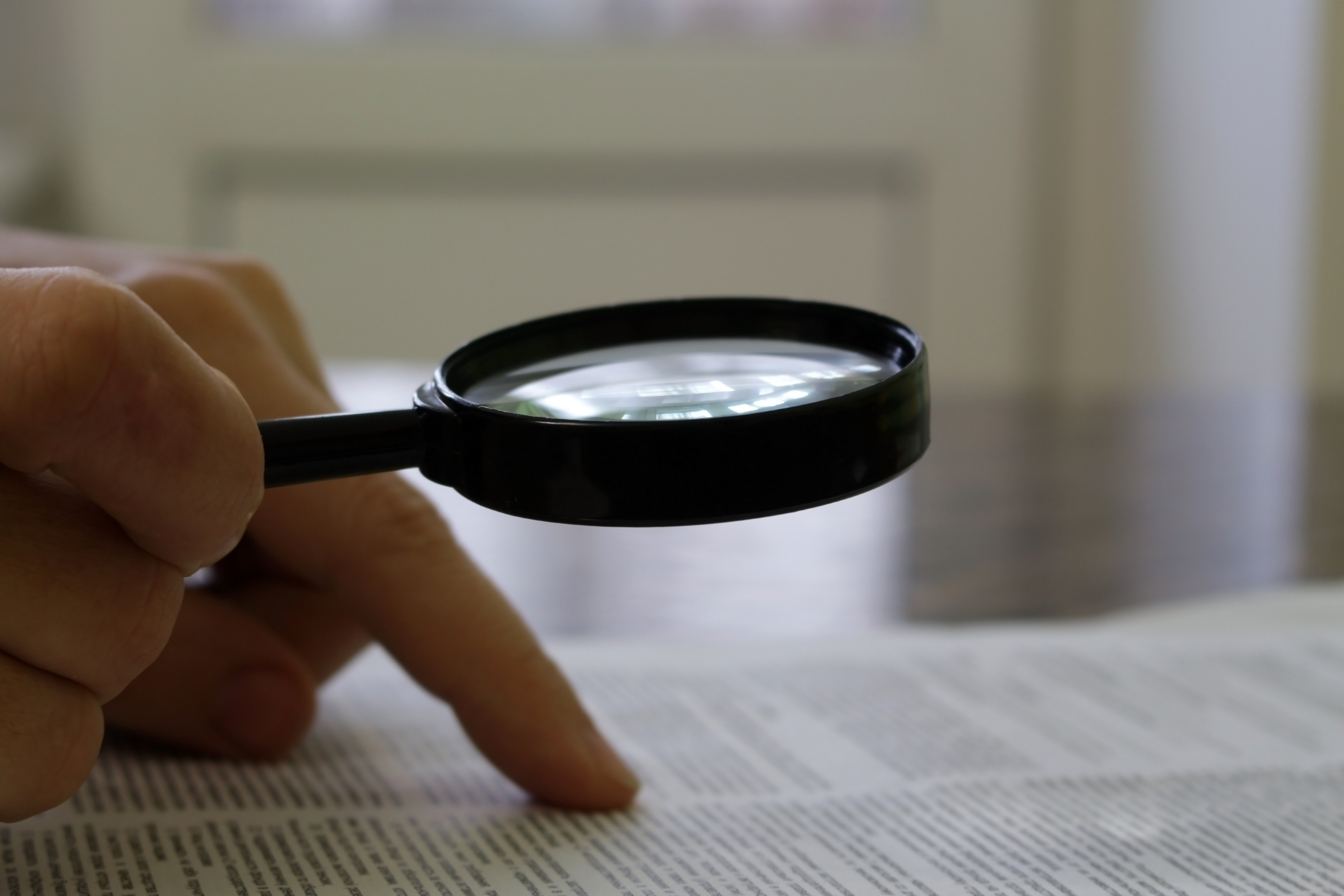 Person going over a document with a magnifying glass