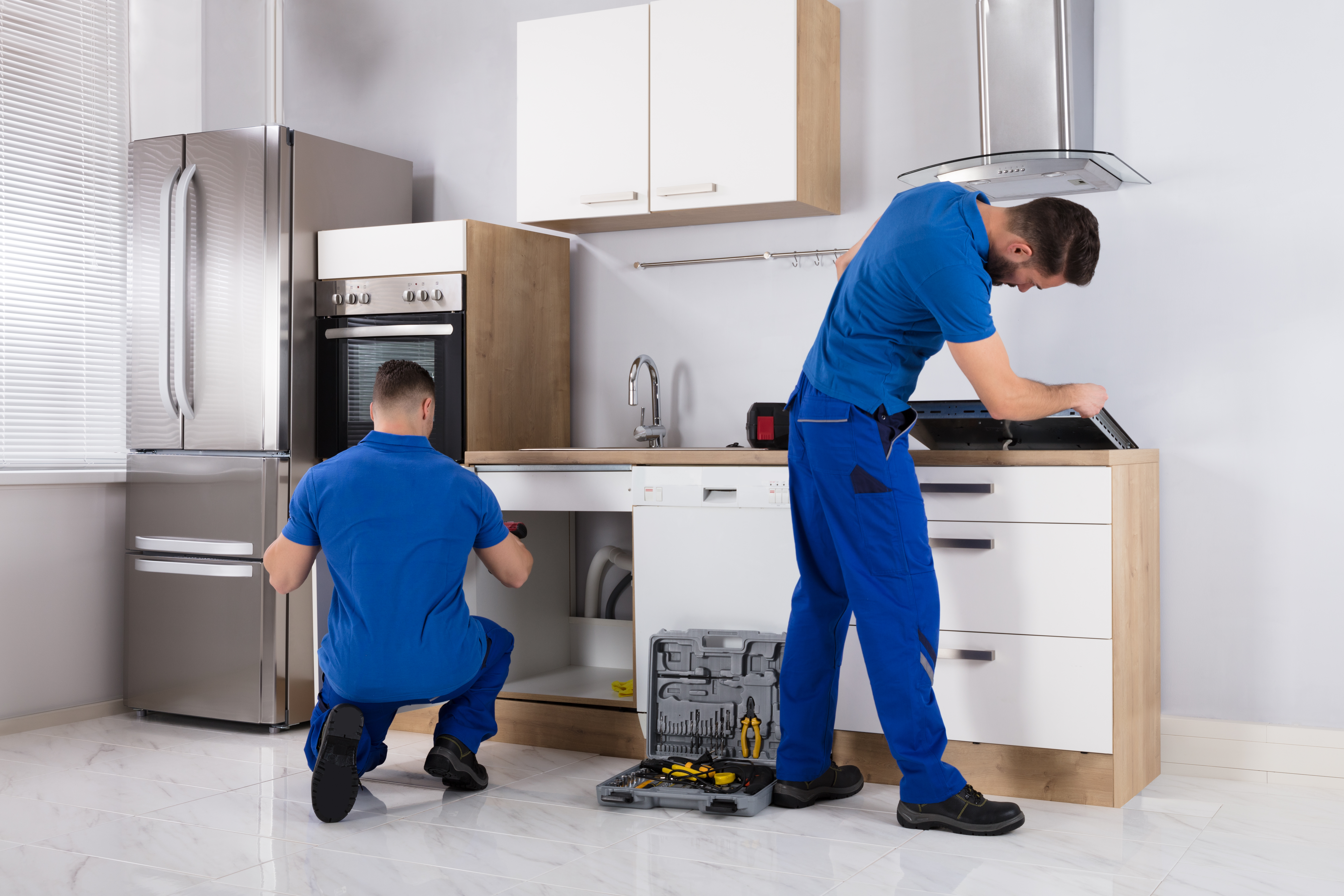 Two men installing appliances in a kitchen