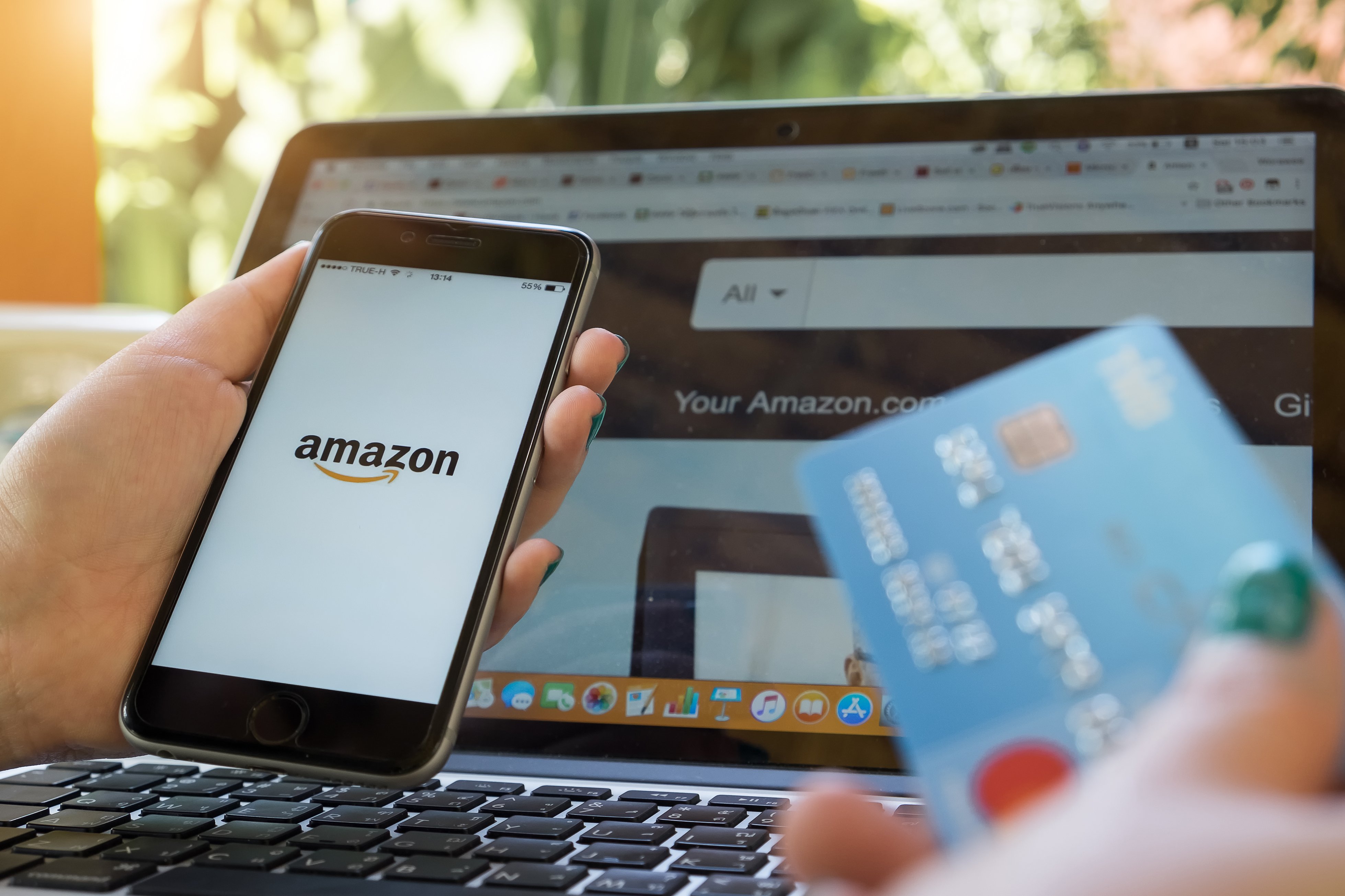Person holding a credit card and a smartphone with the Amazon logo on it
