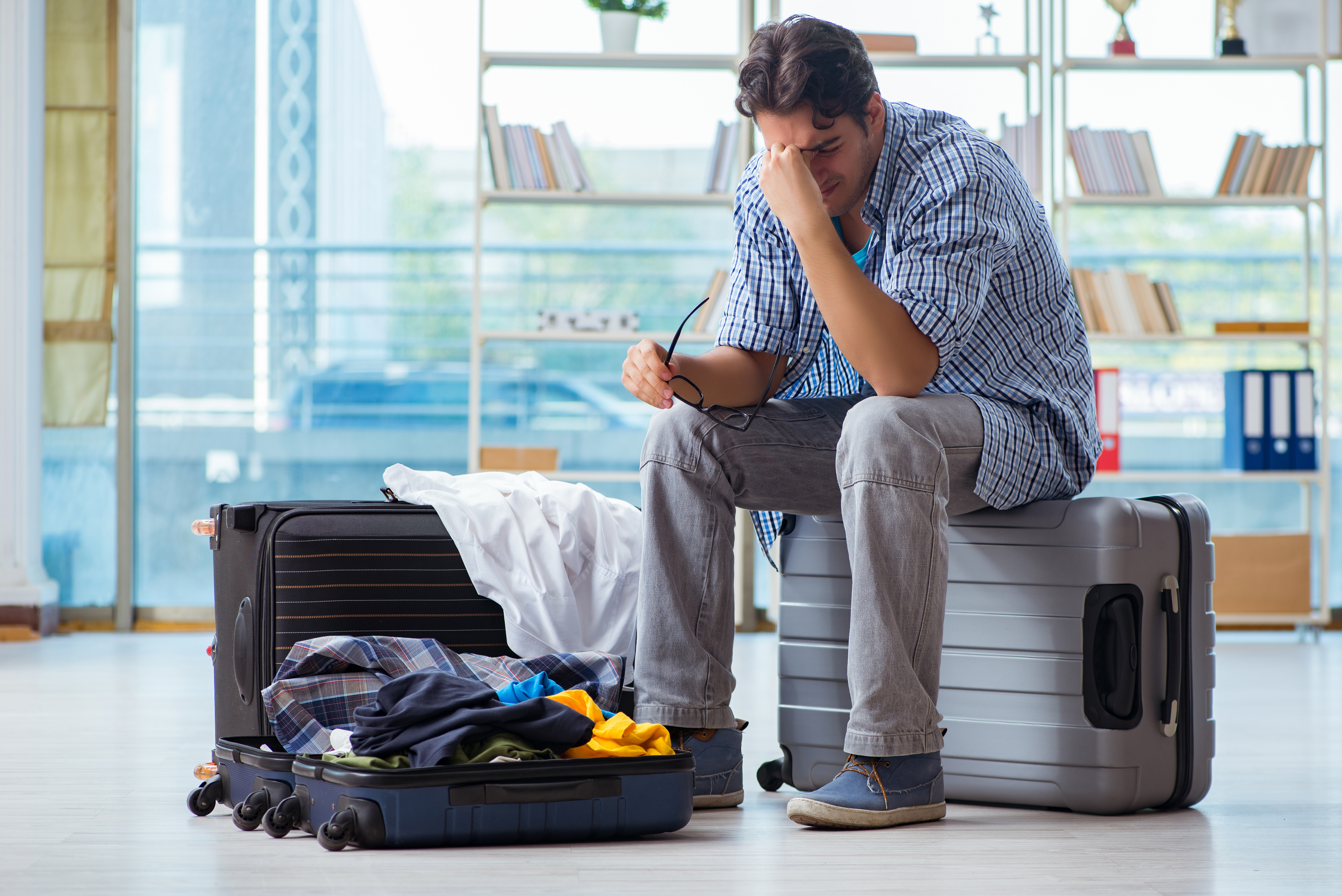 Man sitting on a suitcase looking distressed