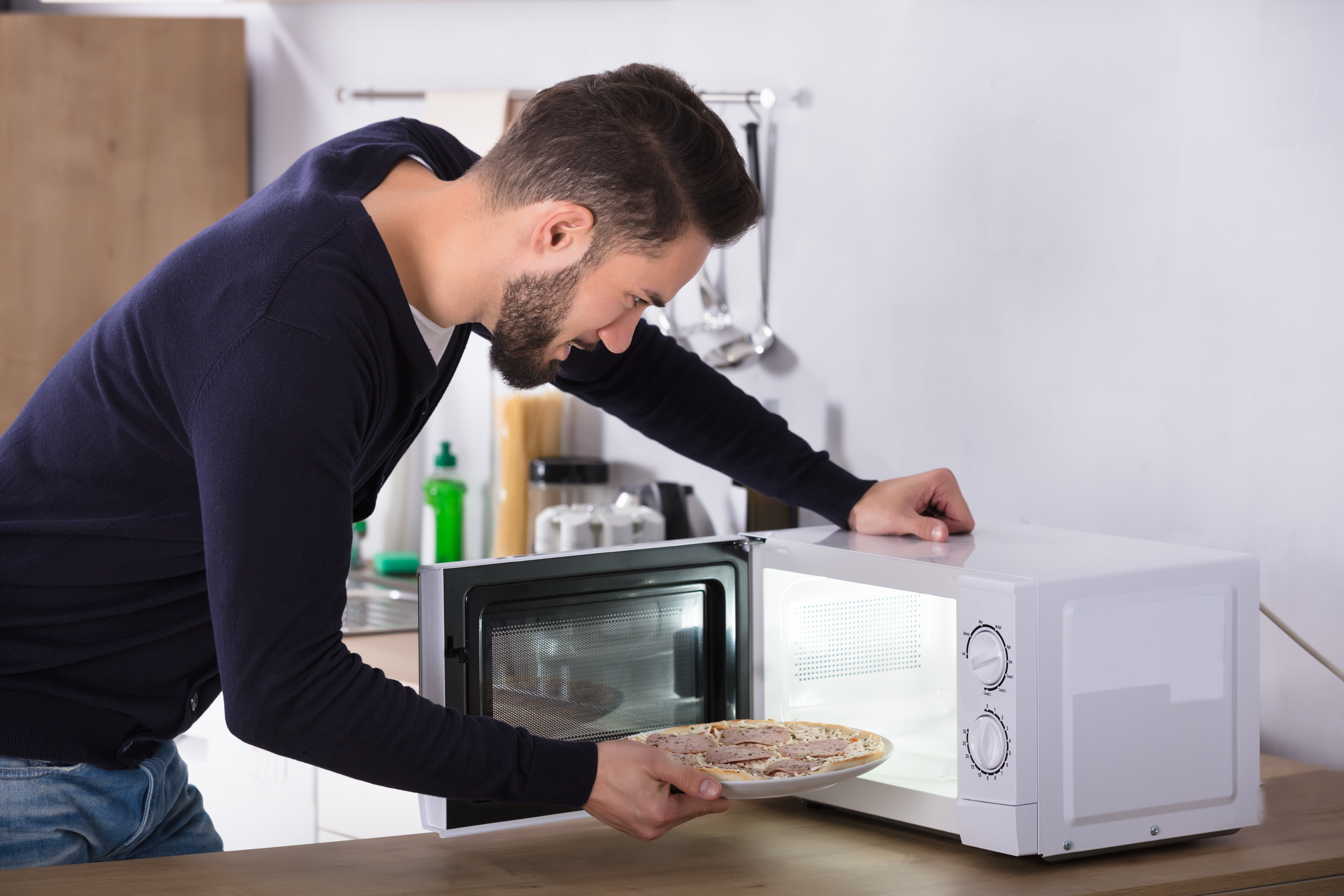 Man putting food into microwave