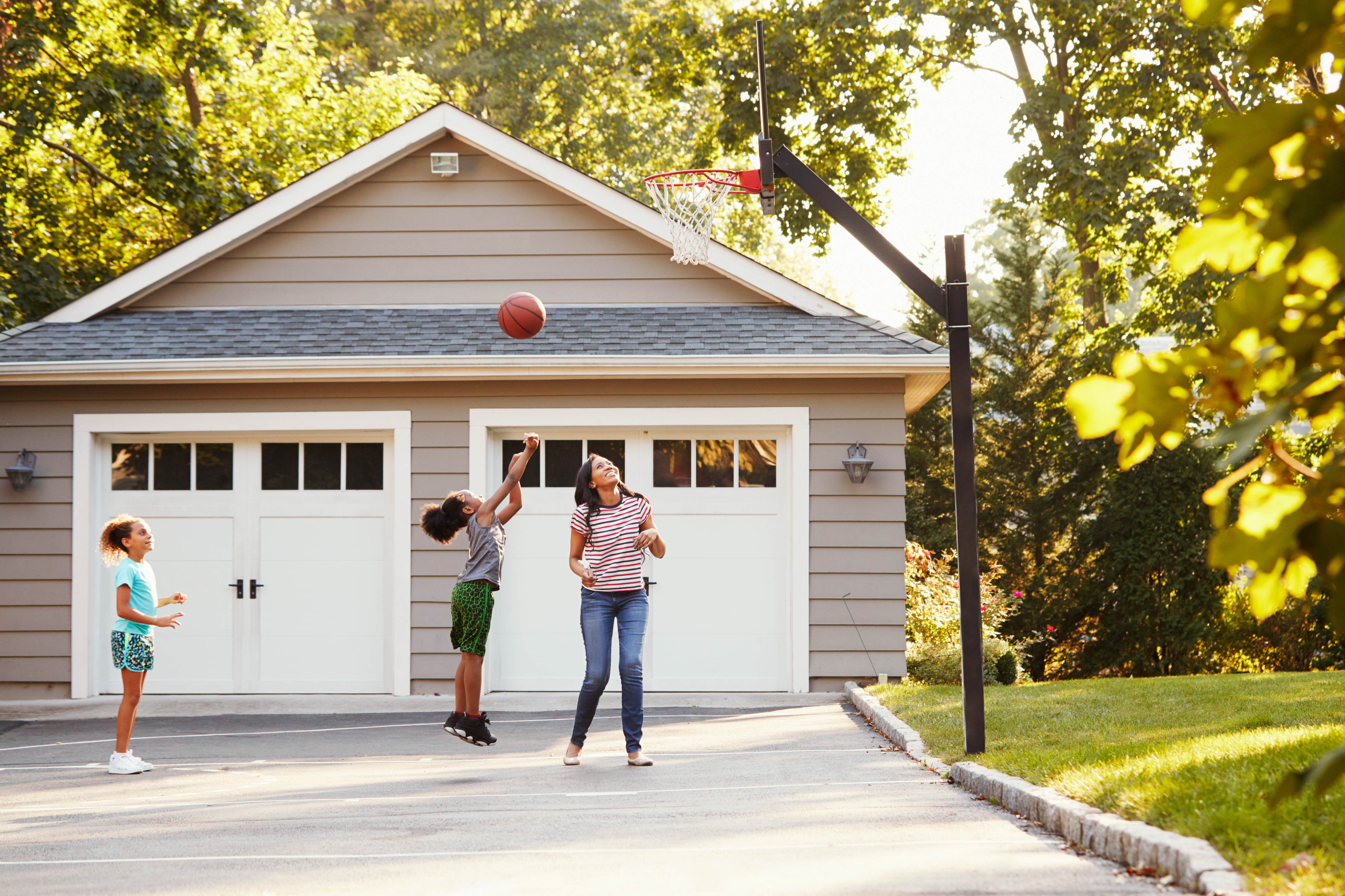 Family playing basketball on a hoop in their driveway